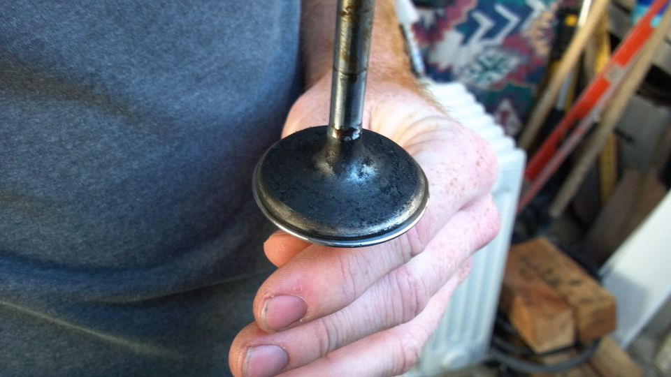 Hand holding a dirty engine valve