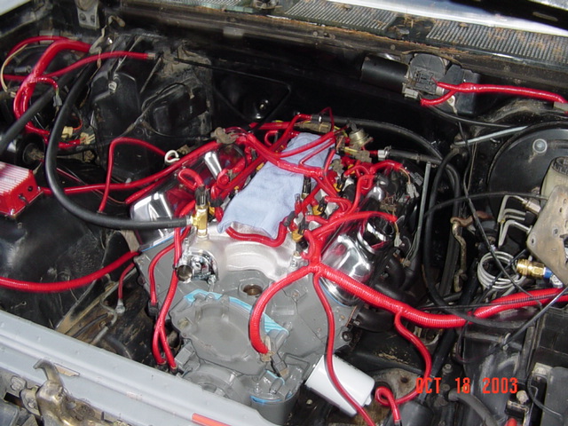 V8 engine in bay with polished intake, tangle of bright red plug wires and a rag stuffed in the valley