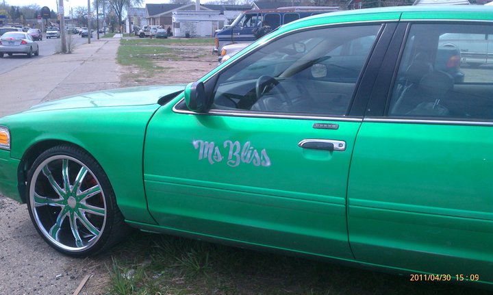 Green sedan with chrome rims and 'Ms Bliss' on the door