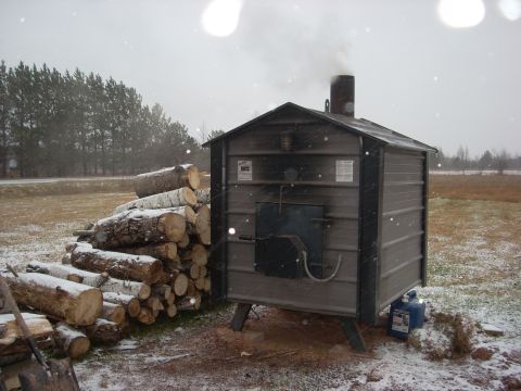 1963 Hummer H3 - A wood boiler operates in a snowy outdoor setting, with a stack of firewood nearby.