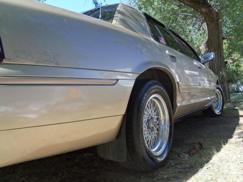 2000 Mercury Grand Marquis - Rear quarter view of a tan 2000 Mercury Grand Marquis with aftermarket wheels.
