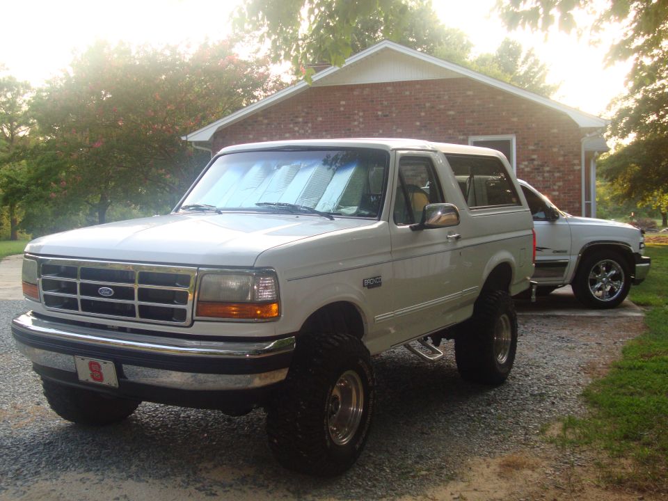 White 1995 Ford Bronco parked in driveway with another truck behind it