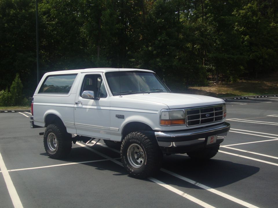 White 1995 Ford Bronco with lifted suspension and off-road tires parked in a lot