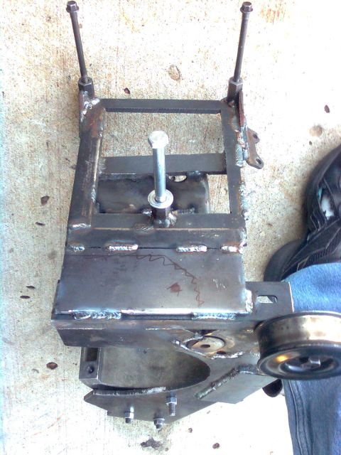 1984 Ford Bronco - A custom-welded metal bracket assembly with bolts and a pulley is shown, likely for an engine modification.