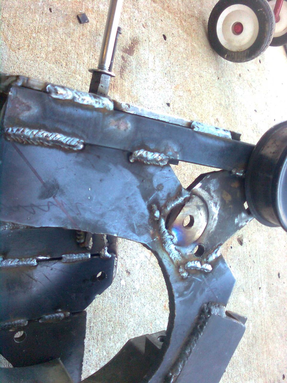 Welded metal bracket with bolt and visible text 'SUPERMOTORS.NET'
