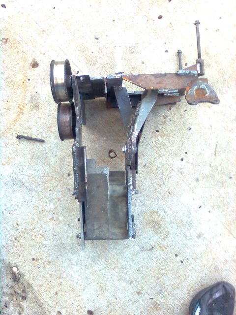 1984 Ford Bronco - A fabricated metal assembly with pulleys and various brackets is shown, likely a custom part for a vehicle modification.