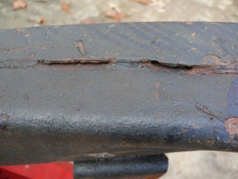 1976 Chevrolet Corvette - Close-up view of a heavily rusted metal frame, showing significant corrosion and a crack.