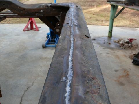 1976 Chevrolet Corvette - A close-up view of a rusty, welded vehicle frame section supported by jack stands and a floor jack.