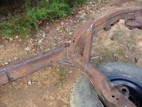 1976 Chevrolet Corvette - A heavily rusted vehicle frame, showing signs of repair with fresh welds, rests on the ground.