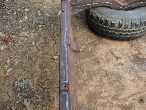 1976 Chevrolet Corvette - A section of a car frame, showing welds and rust, with a tire visible in the background.