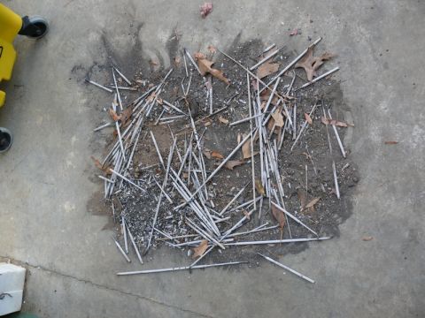 1976 Chevrolet Corvette - A collection of welding rods lies scattered on a concrete surface, mixed with dry leaves and debris.