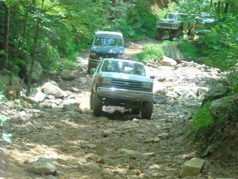 1989 Ford Bronco - A 1987 Ford Bronco navigates a challenging rocky trail with other vehicles behind it.