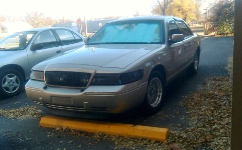 2000 Mercury Grand Marquis - Front view of a 2000 Mercury Grand Marquis parked on a yellow parking bumper.