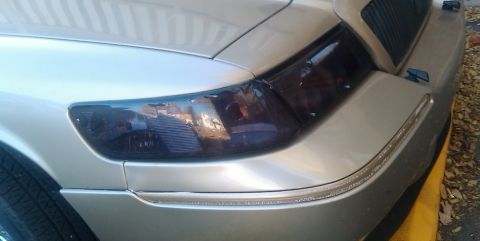 2000 Mercury Grand Marquis - Front corner of a silver 2000 Mercury Grand Marquis, showing tinted headlights and grille detail.