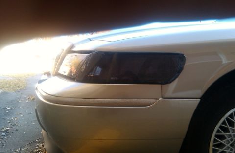 2000 Mercury Grand Marquis - A close-up shot focuses on the tinted headlight of a car, with a website URL visible at the bottom.