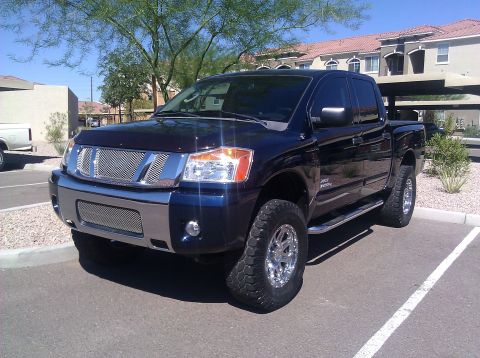2008 Nissan Titan - Dark blue 2008 Nissan Titan pickup truck with aftermarket grille and wheels parked in a lot.