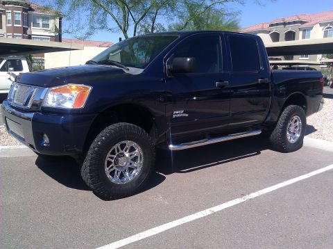 2008 Nissan Titan - This pickup truck is parked in a lot with buildings and trees in the background.