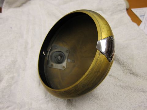 1987 Dodge 1500 - A close-up view of a vintage brass headlight housing, showing its internal mounting bracket and decorative trim.