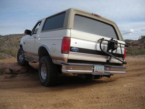 1995 Ford Bronco - Rear view of a 1995 Ford Bronco on a dirt path, equipped with a spare tire carrier.