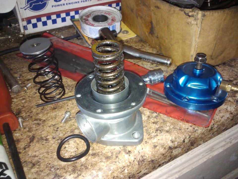Fuel pressure regulator and disassembled spring assembly on a workbench
