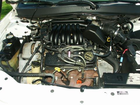 2001 Ford Taurus - Engine bay of a white 2001 Ford Taurus, showing the V6 engine and various components.