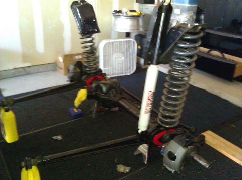 1995 Ford Bronco - Suspension parts, including shocks and springs, are laid out on a dark surface in a garage.