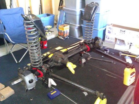 1995 Ford Bronco - Disassembled front axle and suspension parts laid out on a garage floor, suggesting a repair or upgrade project.
