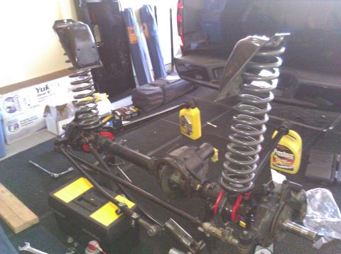 1995 Ford Bronco - Suspension components are disassembled and ready for work in a garage setting.