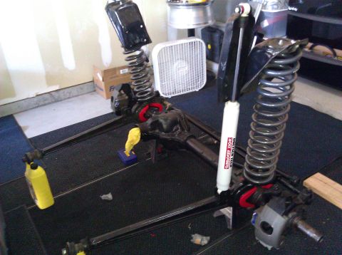 1995 Ford Bronco - Front axle assembly with shocks and springs, likely for an off-road vehicle, is laid out on a mat.