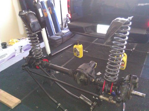 1995 Ford Bronco - Front axle assembly with coil springs and shocks, red spring spacers, likely for an off-road vehicle modification.