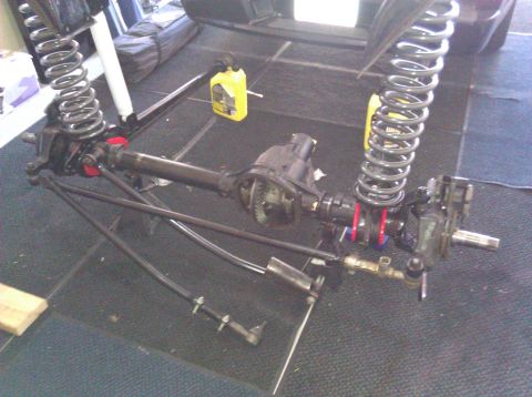 1995 Ford Bronco - Close-up of a vehicle's front axle and suspension system, likely undergoing maintenance or modification.