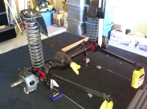 1995 Ford Bronco - Disassembled front axle and suspension components are laid out on the floor.