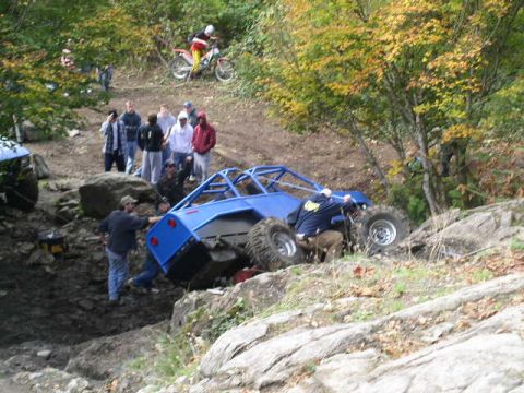 1979 Ford Bronco - Off-road buggy attempts to climb a steep, rocky hill with spectators observing.