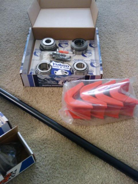 1995 Ford Bronco - Yukon Gear & Axle parts including bearings and bump stops are laid out on a carpeted floor.