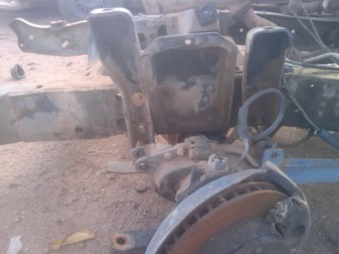 1995 Ford Bronco - Close-up view of disassembled front suspension parts, including a brake rotor and various metal brackets.