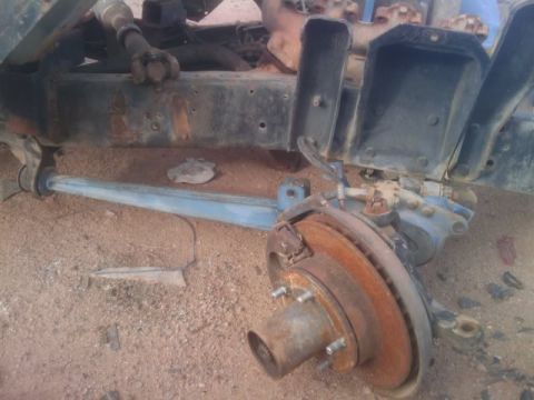 1995 Ford Bronco - Close-up of heavily rusted vehicle frame and suspension parts, showing brake rotor and hub.