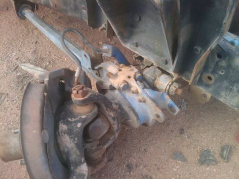 1995 Ford Bronco - Detail of a vehicle's front suspension system, showing various metal components and hardware.