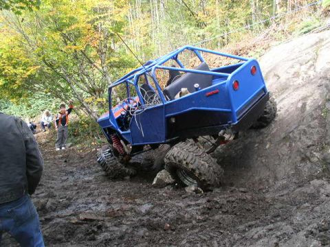 1979 Ford Bronco - Off-road buggy navigates a challenging muddy terrain with spectators watching.