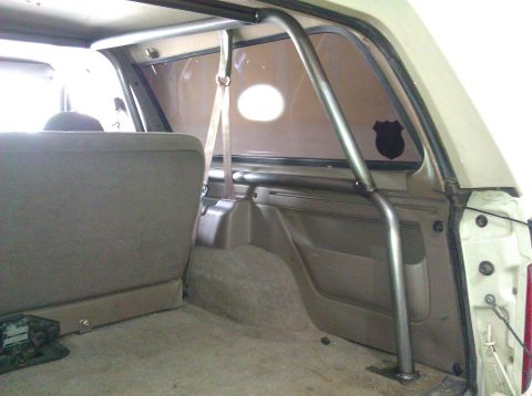 1995 Ford Bronco - A roll cage is visible inside the rear cargo area of a vehicle, obscuring the view of the exterior.