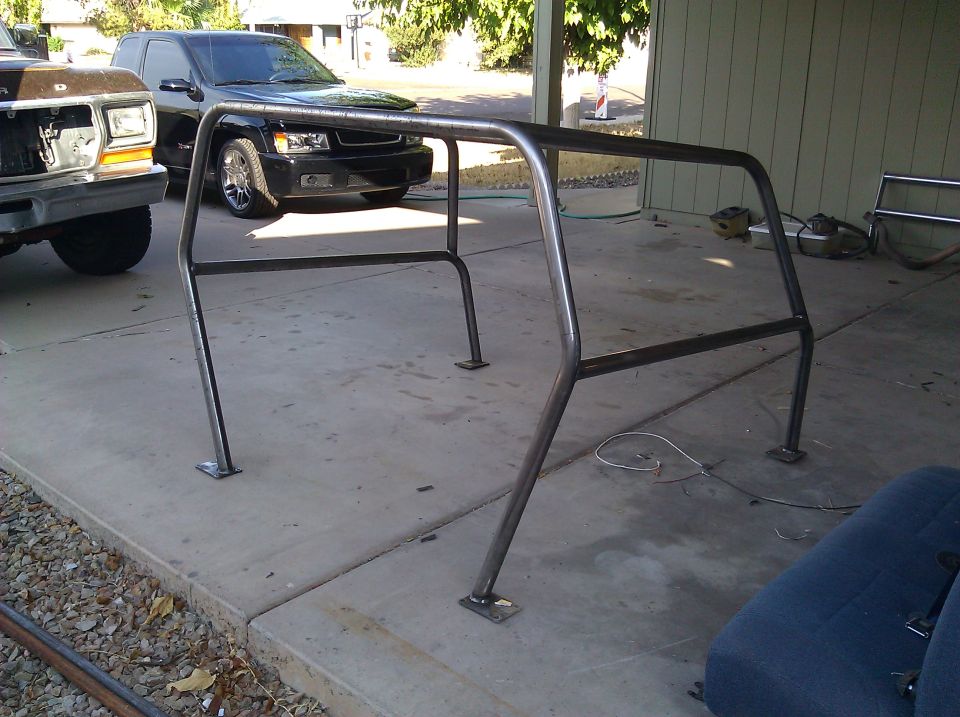 Roll cage in front of a black SUV and a brown Ford Bronco