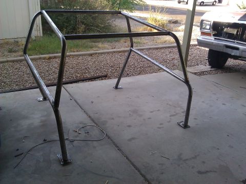 1995 Ford Bronco - A custom-built metal roll cage is shown on a concrete surface, with a vehicle partially visible in the background.