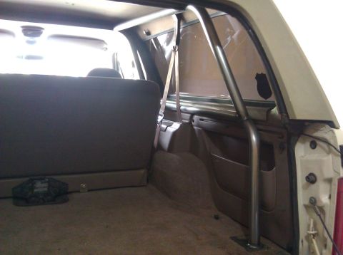 1995 Ford Bronco - The interior of a vehicle is shown, focusing on the rear seating area and a metal roll cage.