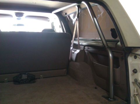 1995 Ford Bronco - The interior of a vehicle shows a metal roll cage structure behind the rear seats.