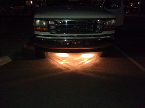 1995 Ford Bronco - Front view of a white Ford truck with underglow lights, showing its grille and headlights.