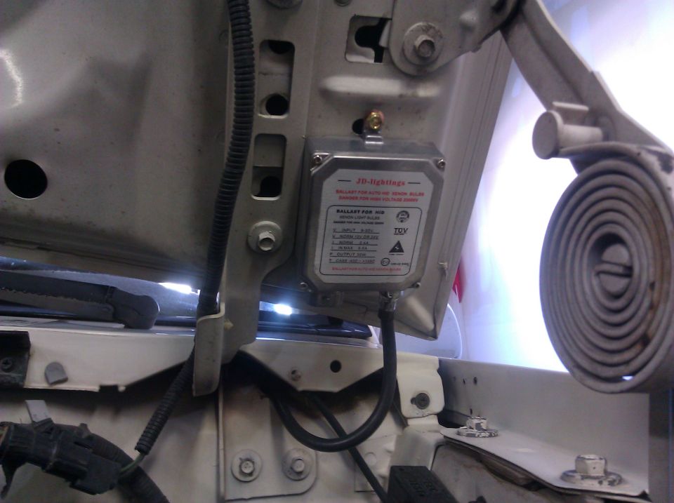 Ballast for HID Xenon light bulbs mounted on a vehicle's engine bay structure