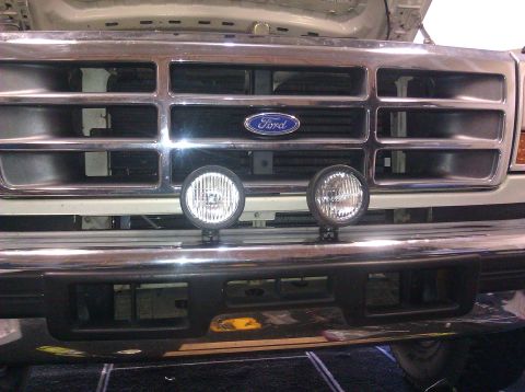 1995 Ford Bronco - Front view of a 1995 Ford Bronco's grille, two round fog lights mounted below the chrome bumper.