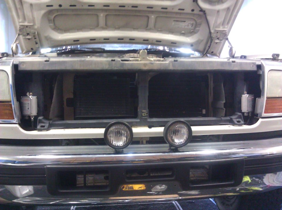 front of truck with hood open, showing grille and two round auxiliary lights mounted on bumper