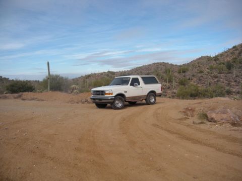 1995 Ford Bronco - This 1995 Ford Bronco is seen in a desert environment, parked on a dirt road under a partly cloudy sky.