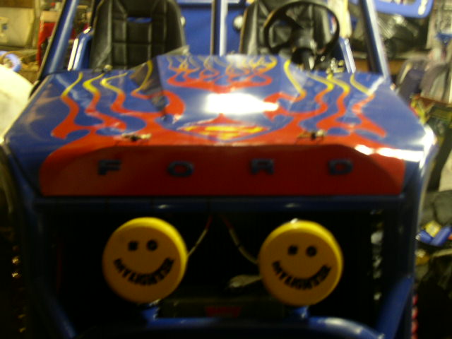 Buggy front with blue paint, red and yellow flames, and smiley face lights. Reads 'FORD' on the hood