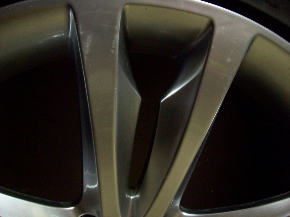Close-up of a silver alloy wheel with five split spokes and some scuff marks